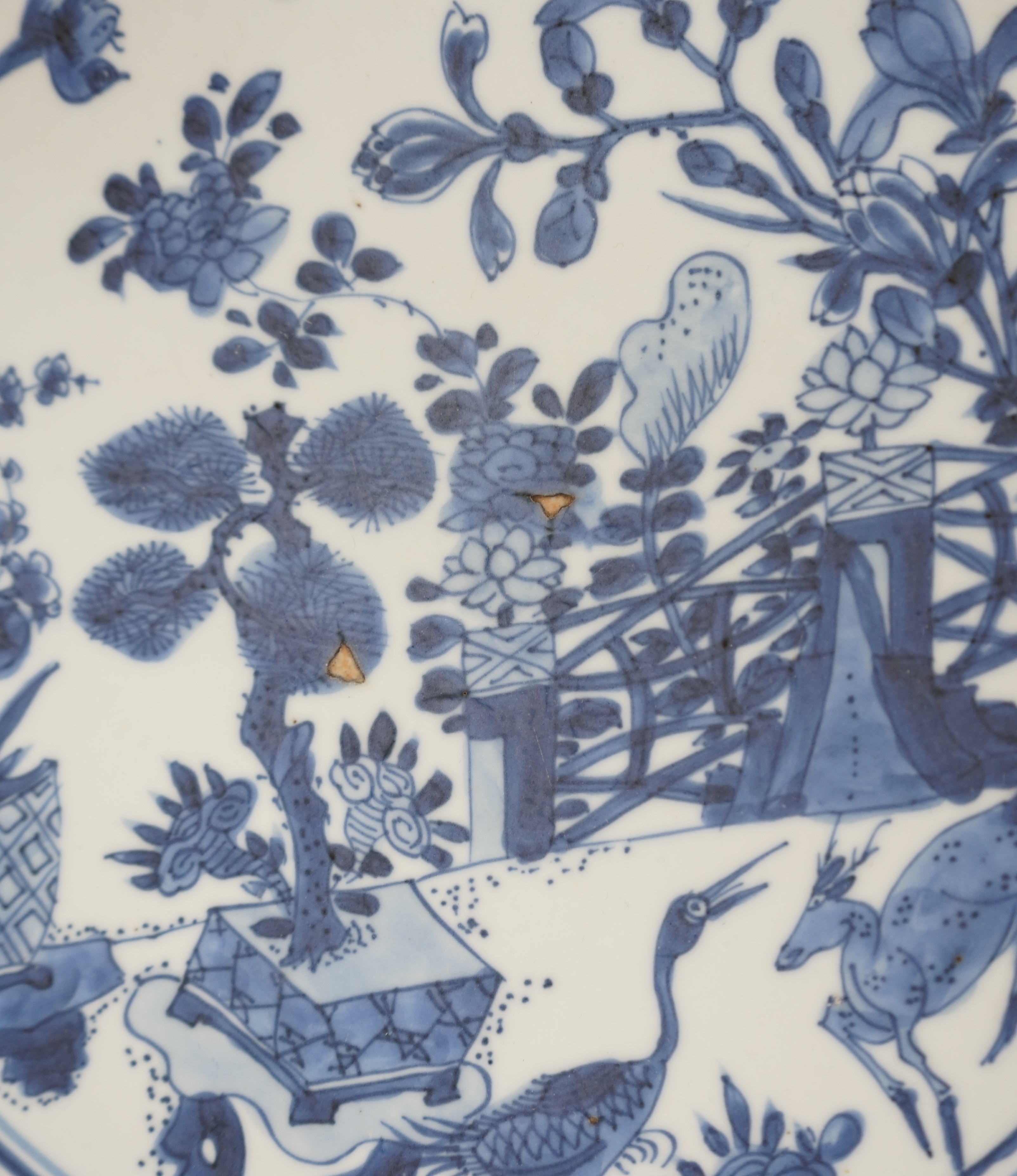 A pair of Chinese blue and white ‘garden’ dishes, Kangxi period, fritting and glaze chips
